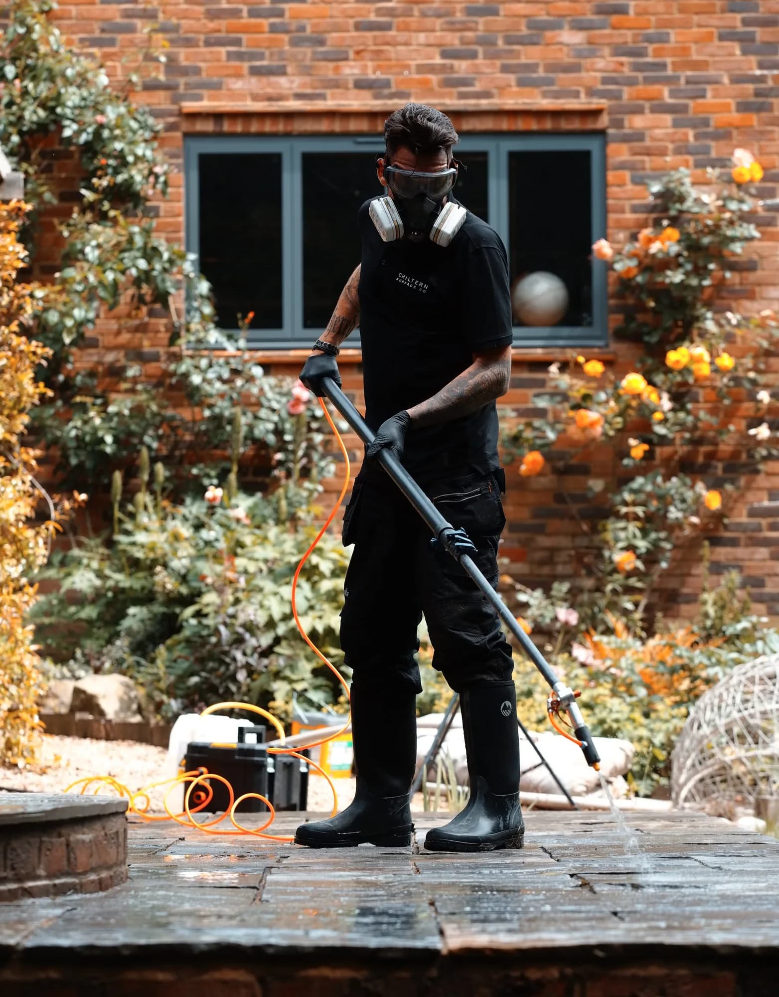 Chiltern Surface Co technician in a respirator, goggles and gloves spraying Chiltern EverGuard™ onto a patio