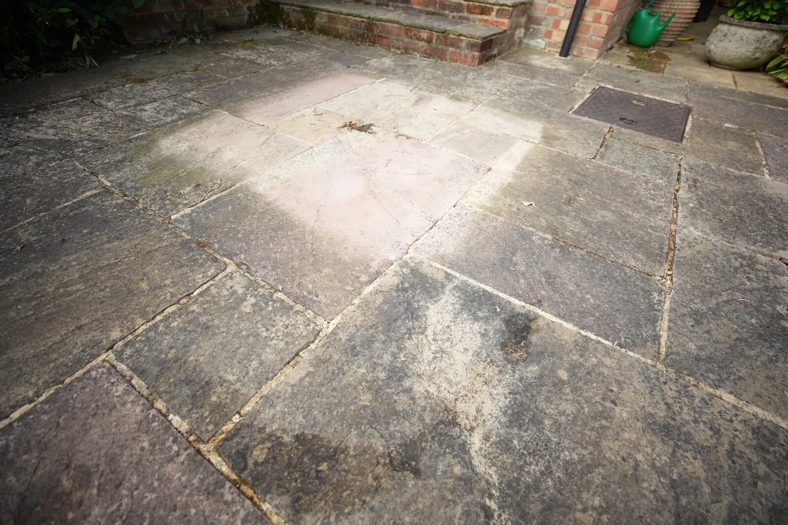 Sandstone patio in Oxford before cleaning, blackened by black spot and organic staining