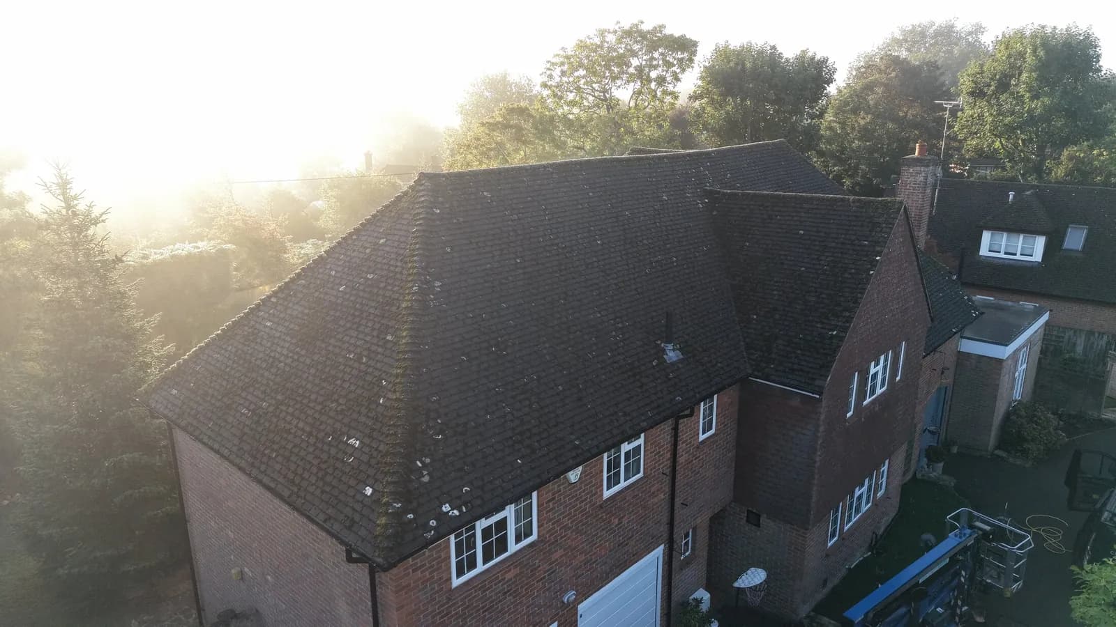 Detached family home in Great Missenden at first light, its concrete tile roof dark with moss and lichen before cleaning