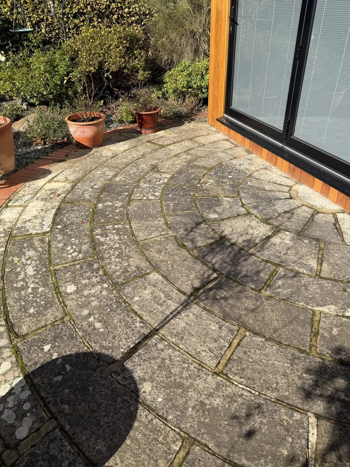 The circular sandstone terrace at the garden room the day before the works, grey and spotted with lichen