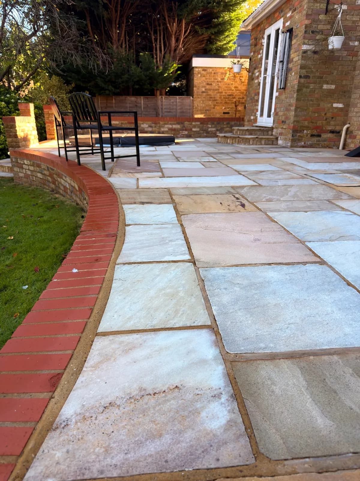 The red brick edging and coping along the lawn after cleaning, beside the finished sandstone