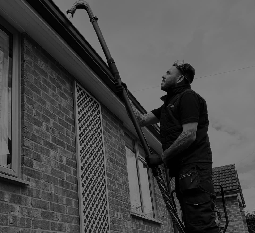 Chiltern Surface Co operative clearing guttering with a vacuum from a properly footed ladder
