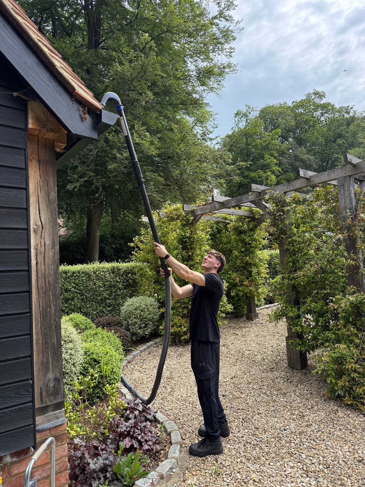 Gutter being cleared with a pole-fed gutter vacuum from ground level