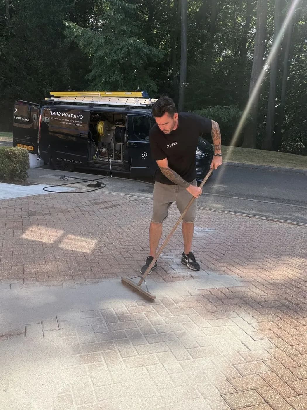 Chiltern Surface Co technician brushing polymeric sand into the joints of cleaned block paving