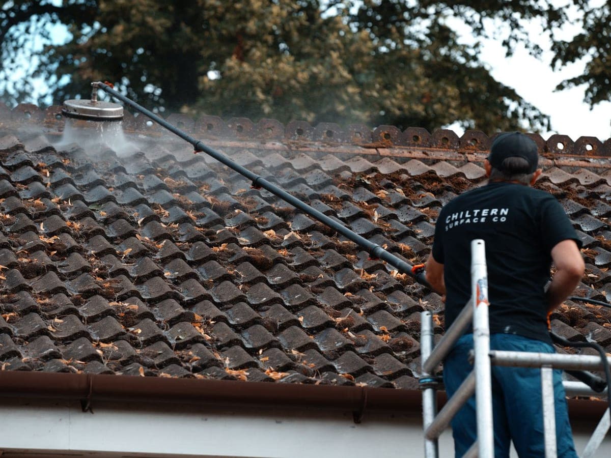 Chiltern Surface Co operative soft washing a heavily mossed tiled roof with a pole-fed rotary head