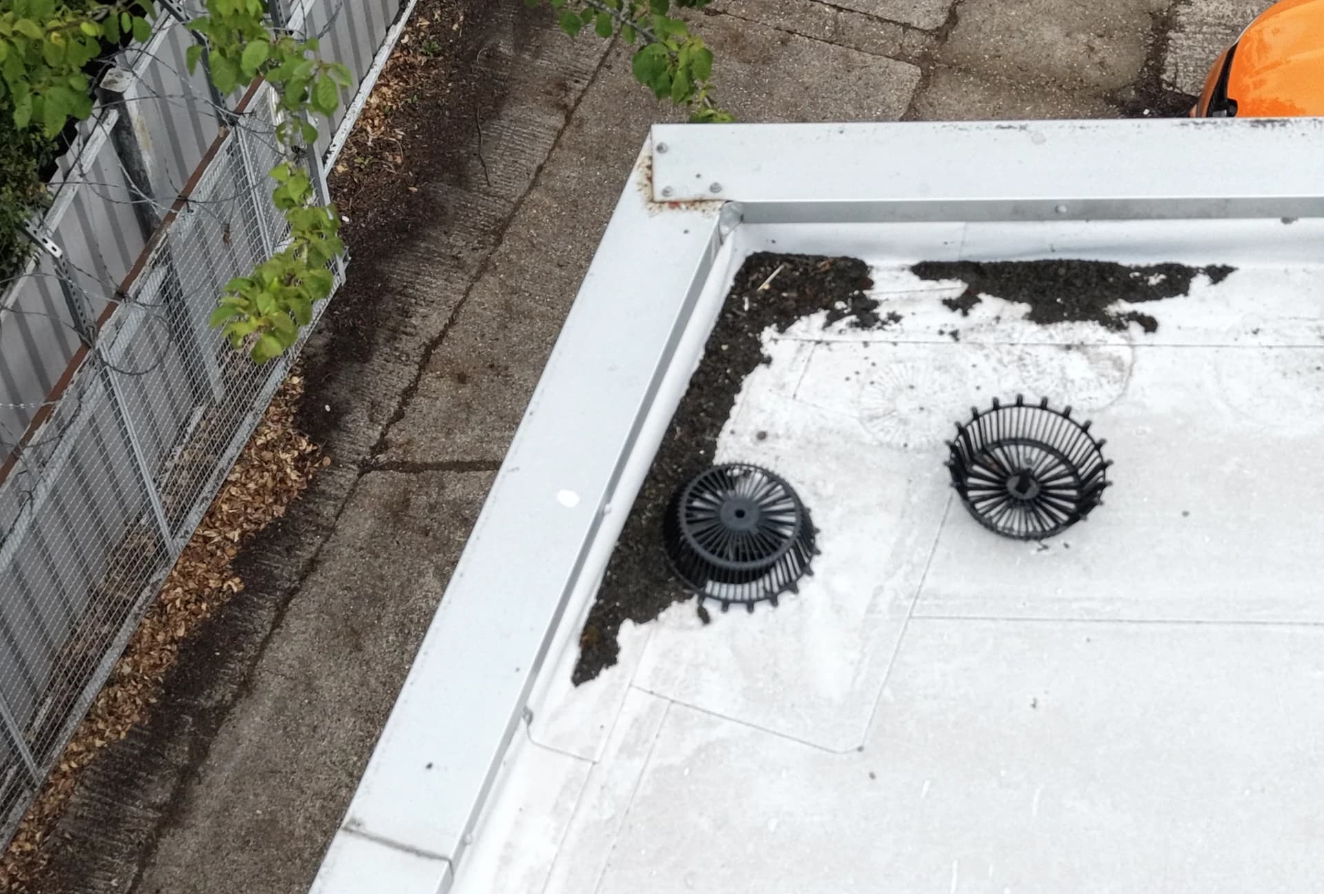 Aerial view of black leaf-guard domes over roof outlets with debris collected on a white membrane