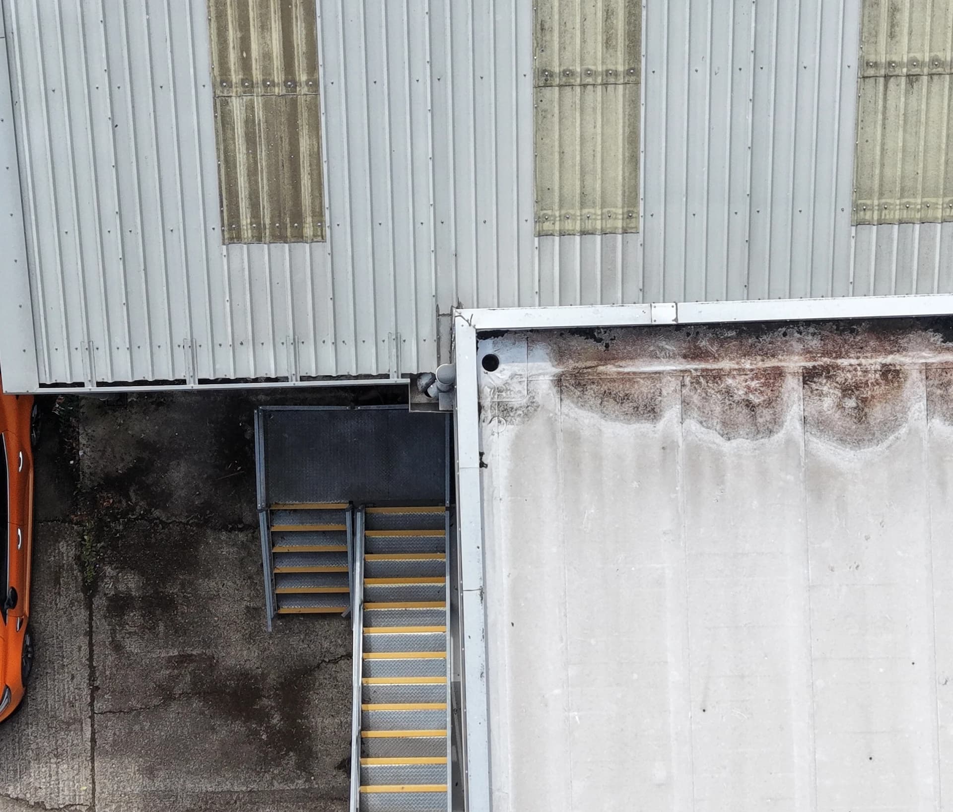 Aerial view of staining along a roof edge with an outlet, a service stair below the parapet
