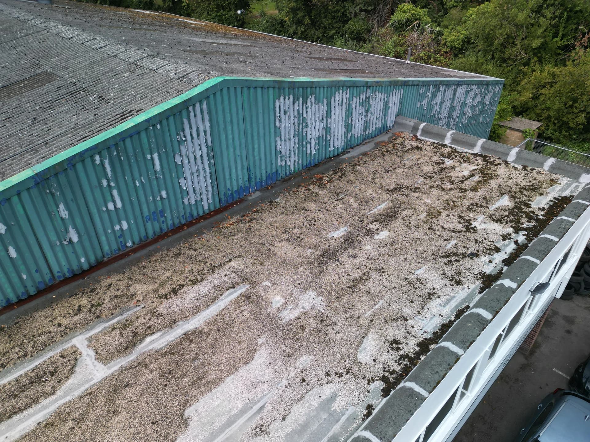 Close oblique of the flat roof edge with stained membrane and green wall cladding.