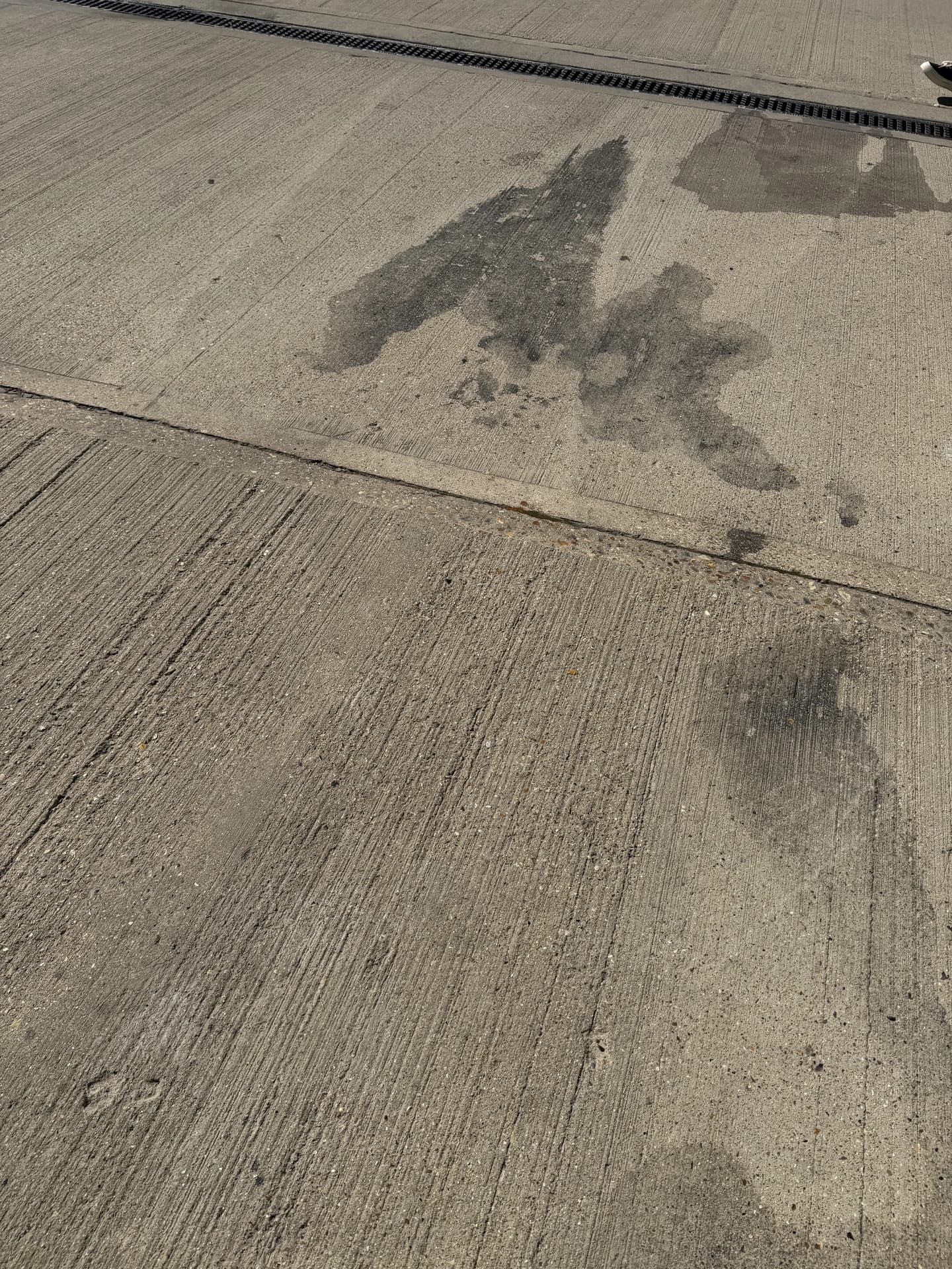 Close view of dark oil staining on tamped concrete with a joint line