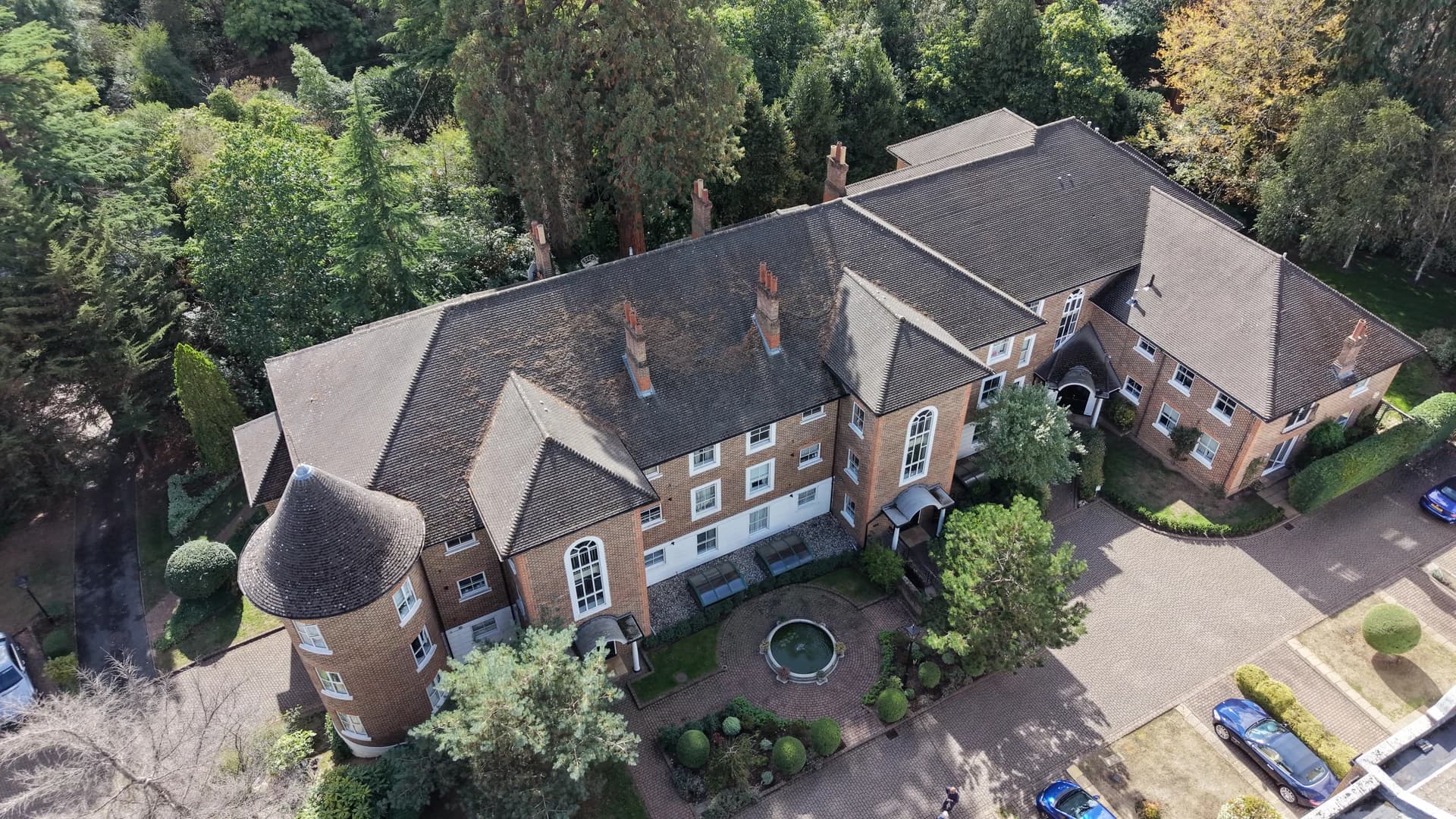 Oblique aerial view of a brick apartment block with a turret and a paved courtyard below
