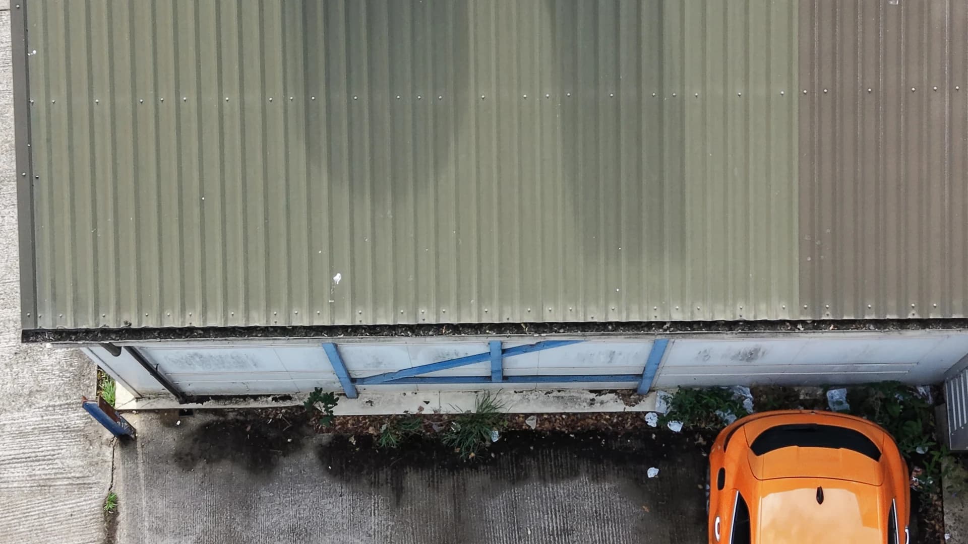 Profiled roof sheeting at the gutter edge with bands of green algae along the troughs