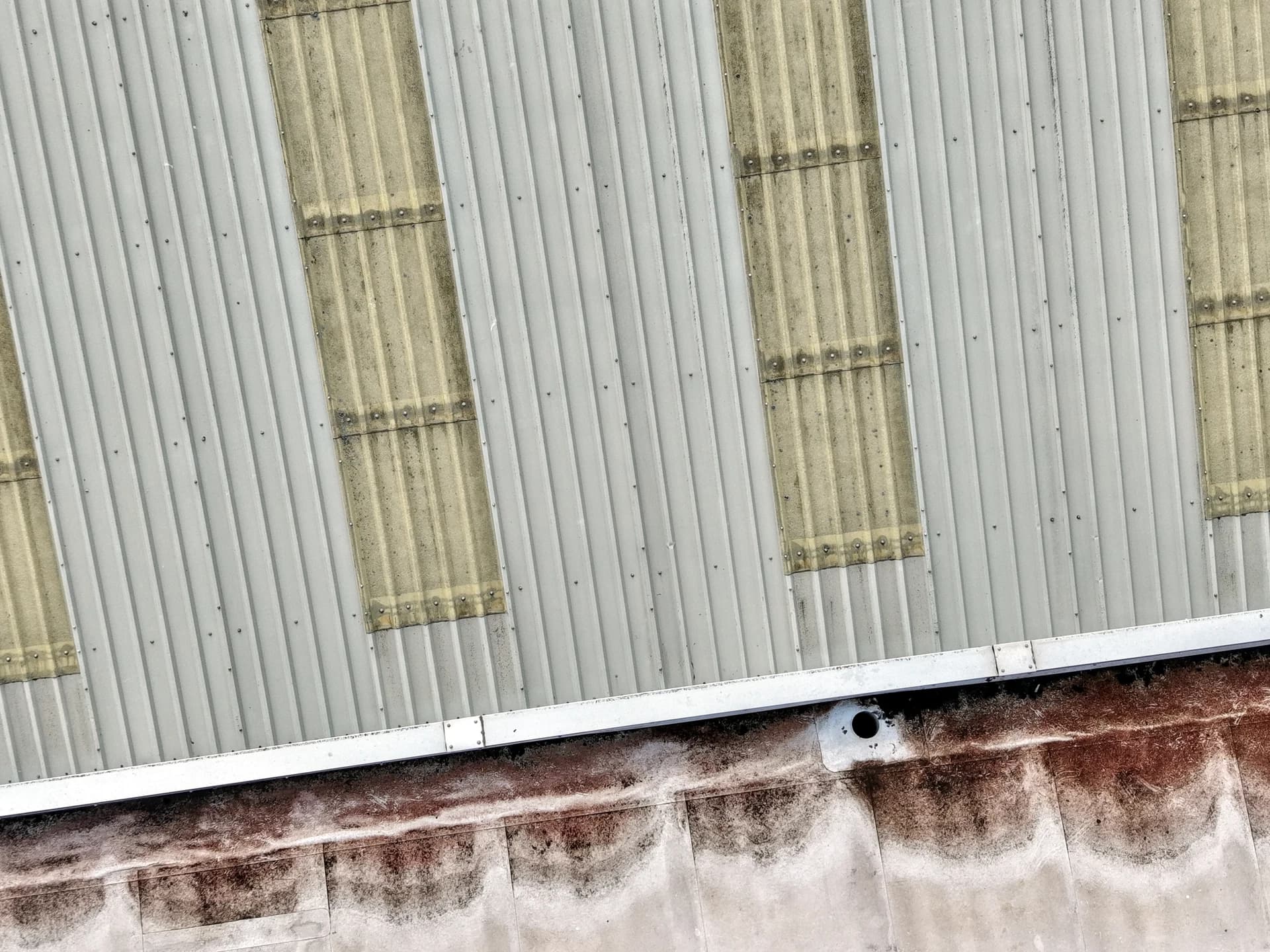 Scalloped algae/rust staining along the foot of a metal parapet.