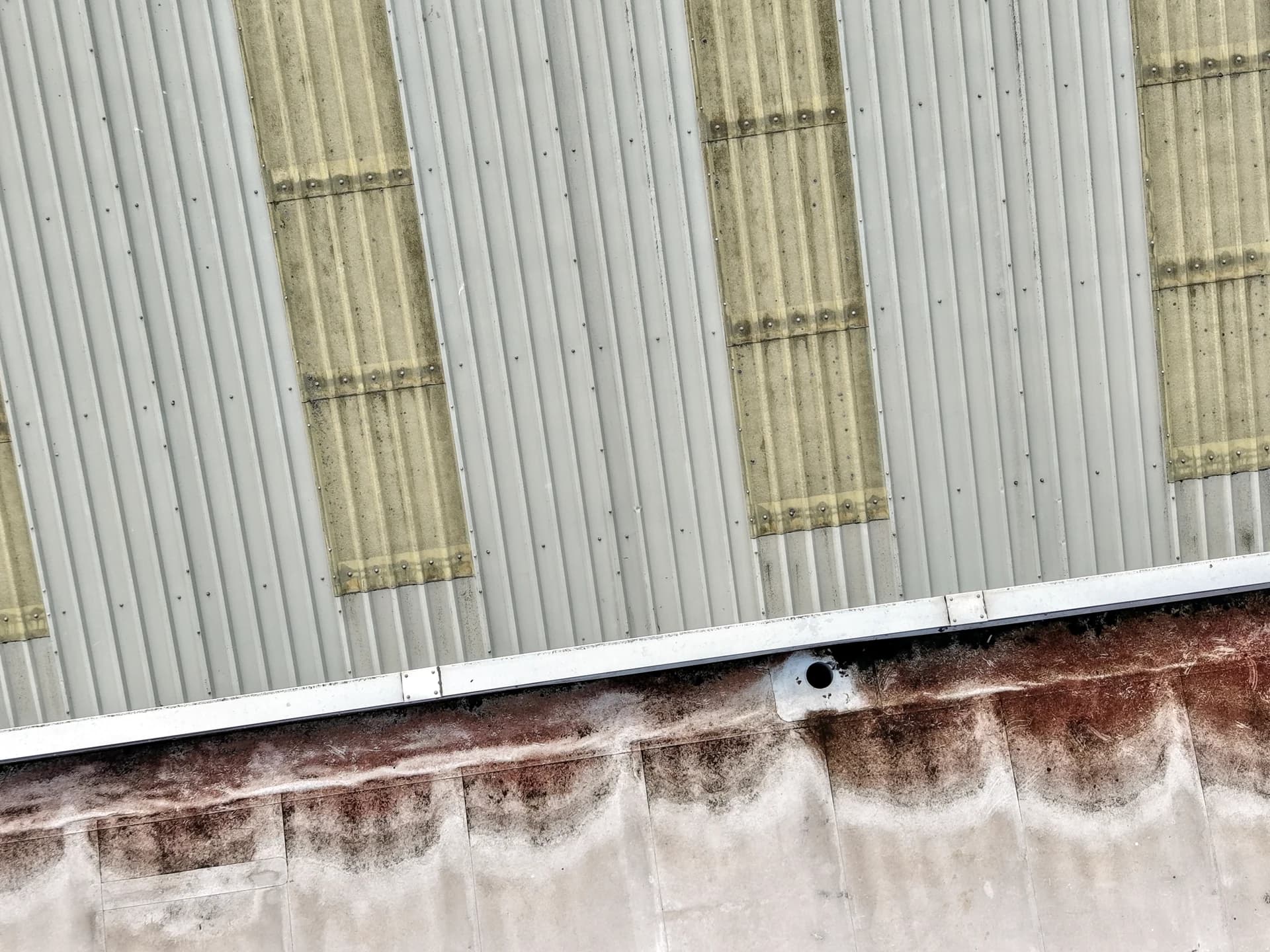Scalloped algae/rust staining along the foot of a metal parapet.