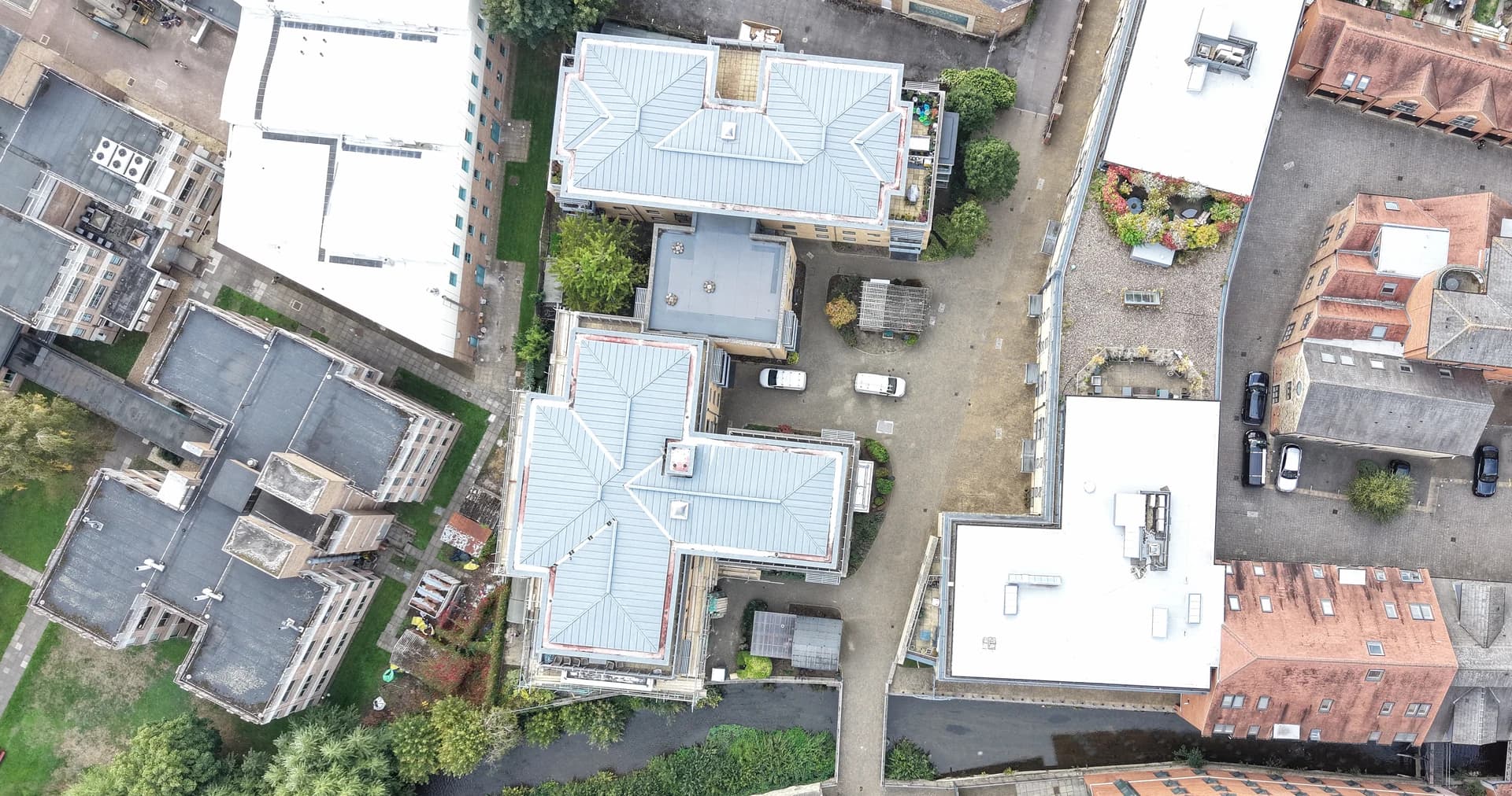 Straight-down aerial view of apartment blocks, a paved courtyard and the surrounding roofs