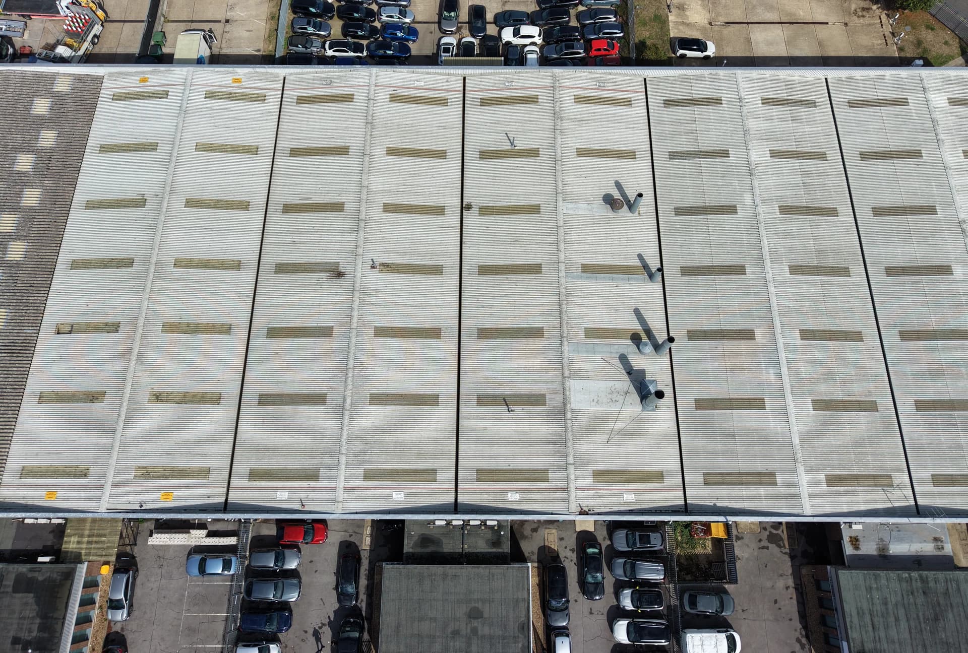 Top-down aerial view of an industrial building with a yard and car parks beside it
