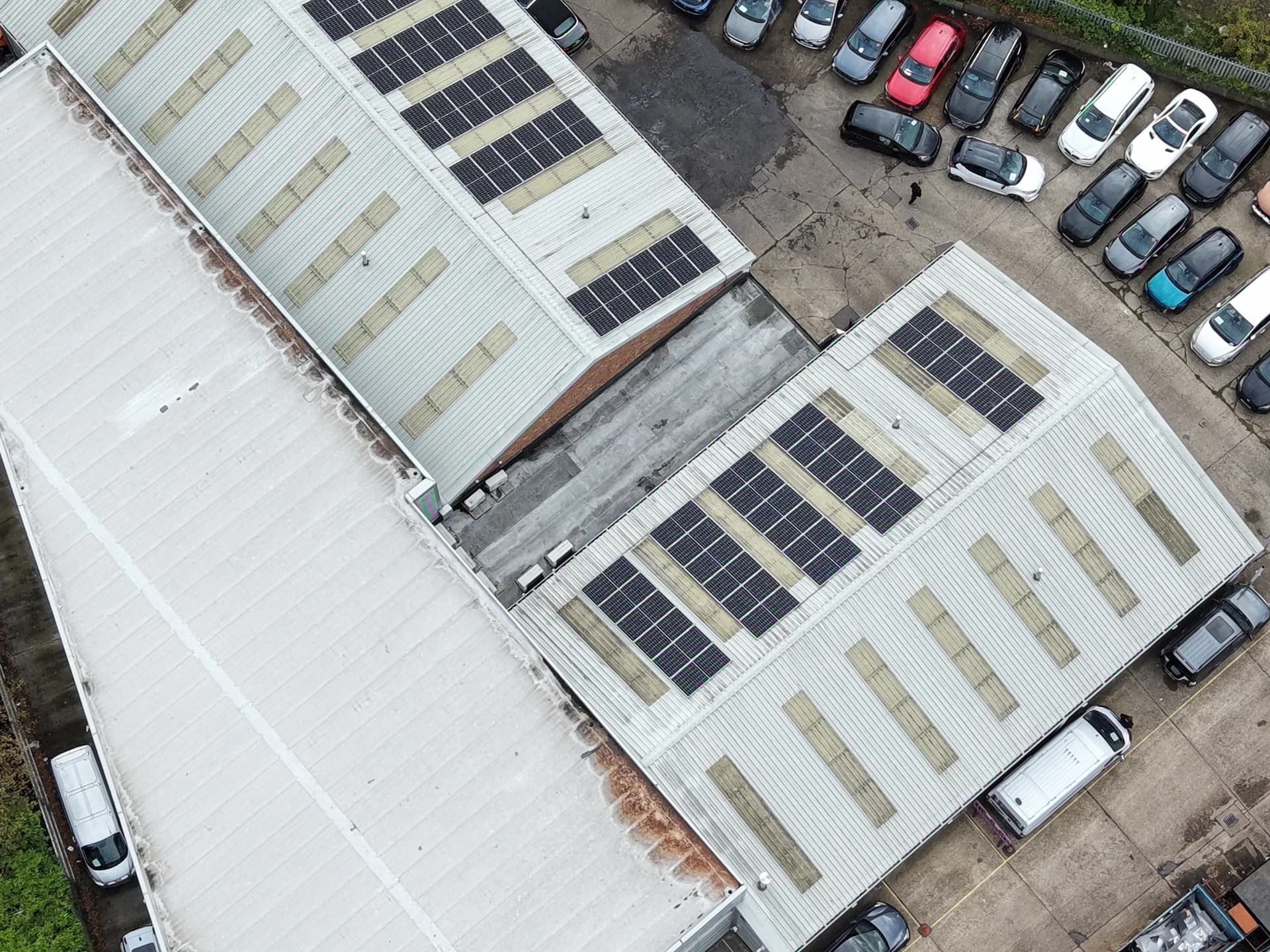 Wide aerial view of commercial units with roofs and a car park beside them