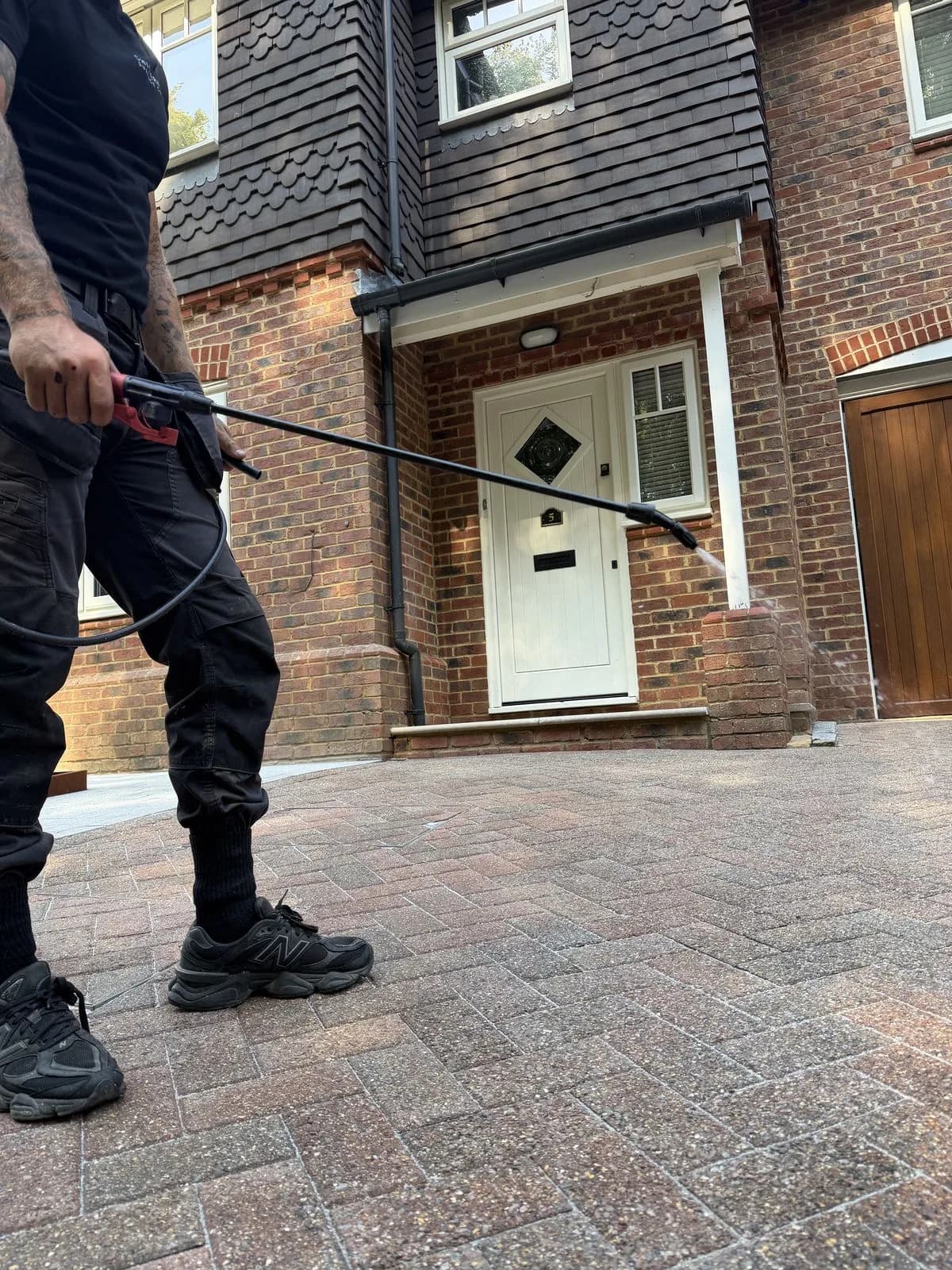 Chiltern Surface Co technician applying Chiltern EverGuard™ biocide across the finished block paved driveway with a spray lance