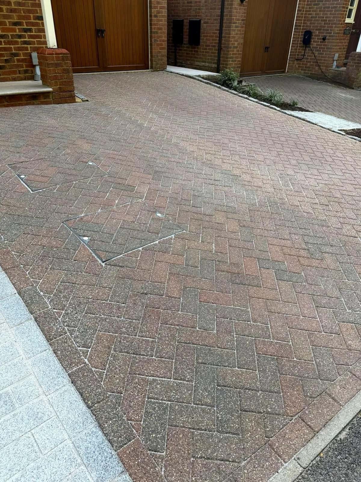 The same driveway after cleaning and polymeric re-sanding, photographed from the same position at the garage end