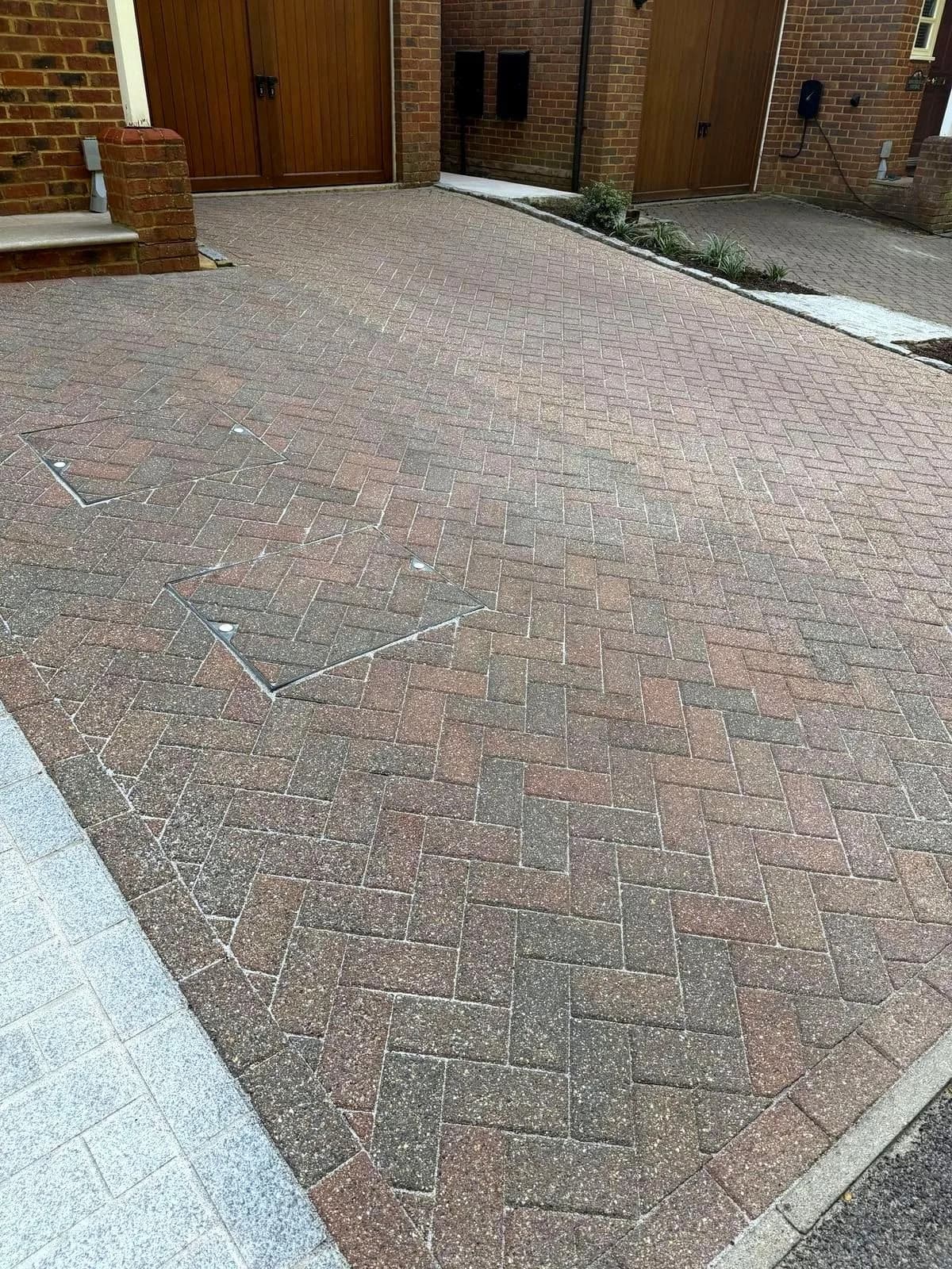The same driveway after cleaning and polymeric re-sanding, photographed from the same position at the garage end