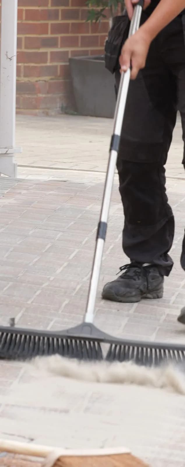 Chiltern Surface Co technician sweeping polymeric sand into the block paving joints