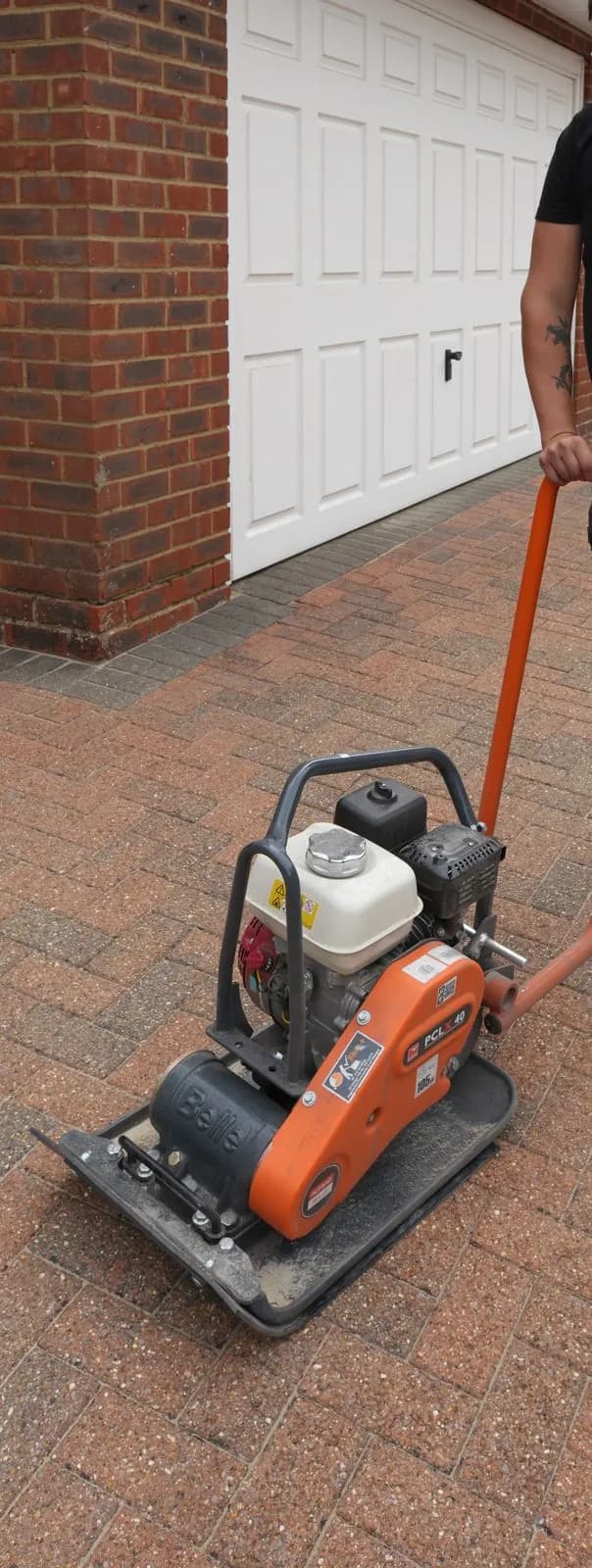 Plate compactor settling the polymeric sand into the block paving joints