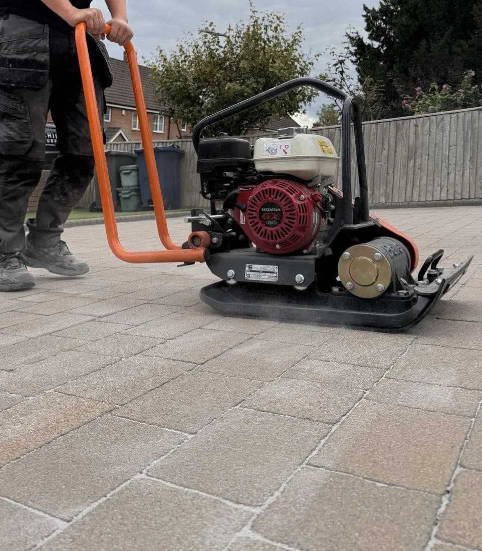 Plate compactor running across the re-sanded block paved driveway in High Wycombe
