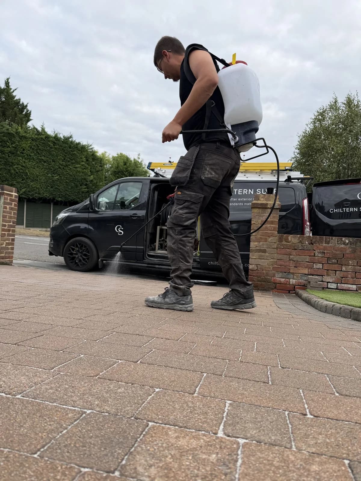 Chiltern Surface Co technician applying Chiltern EverGuard™ biocide treatment to the driveway with a backpack sprayer