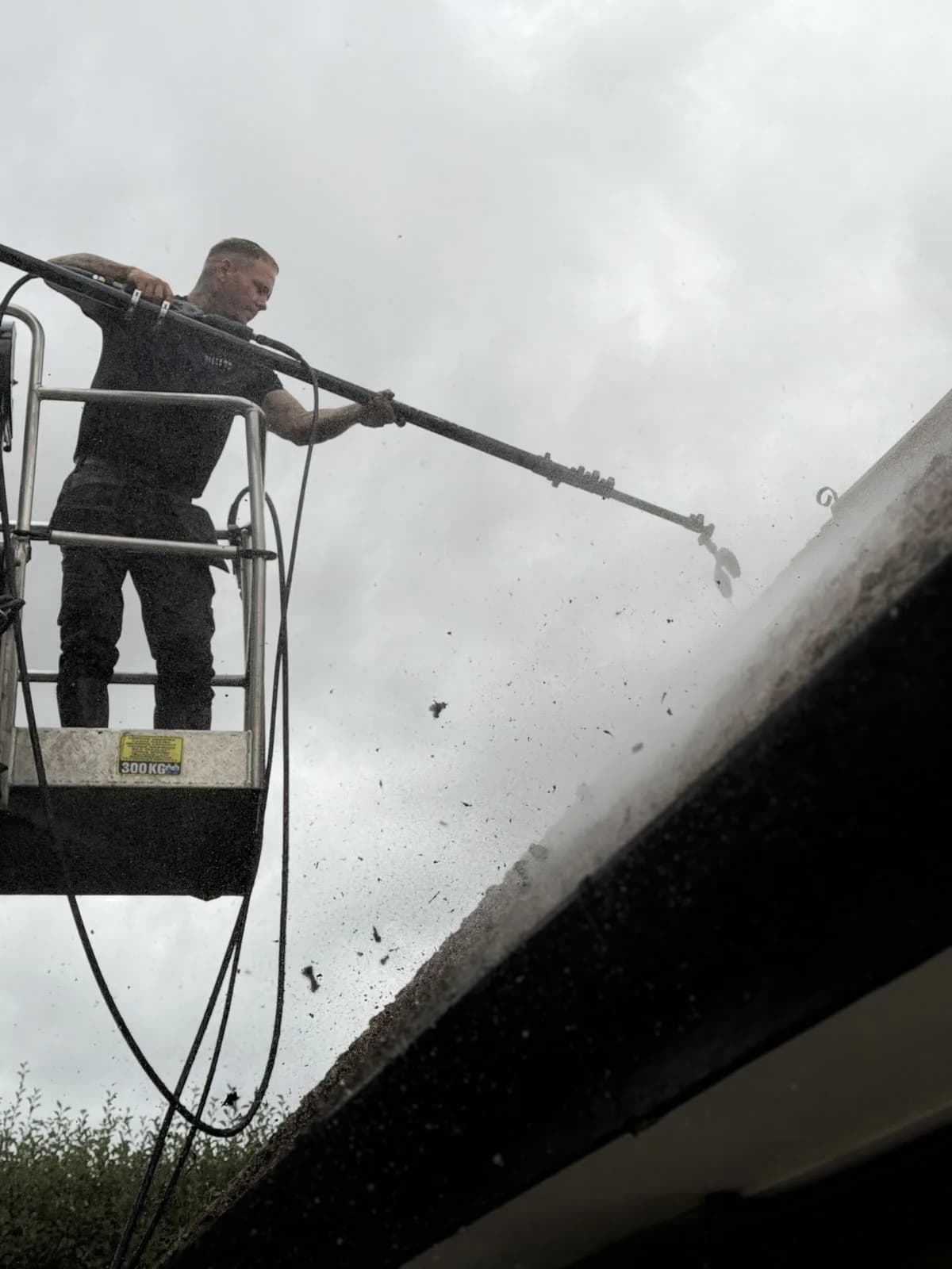 Chiltern Surface Co technician driving the heavy moss off the clay tiles from the cherry-picker basket