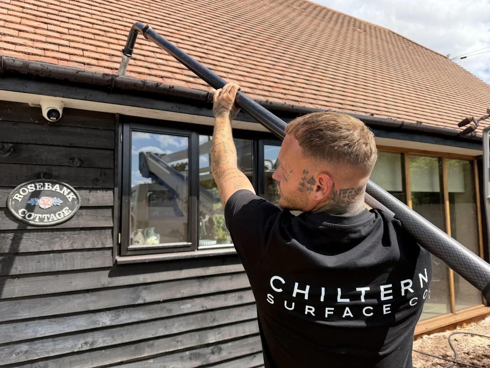 Chiltern Surface Co technician clearing the gutters from the ground with a pole vacuum after the roof clean