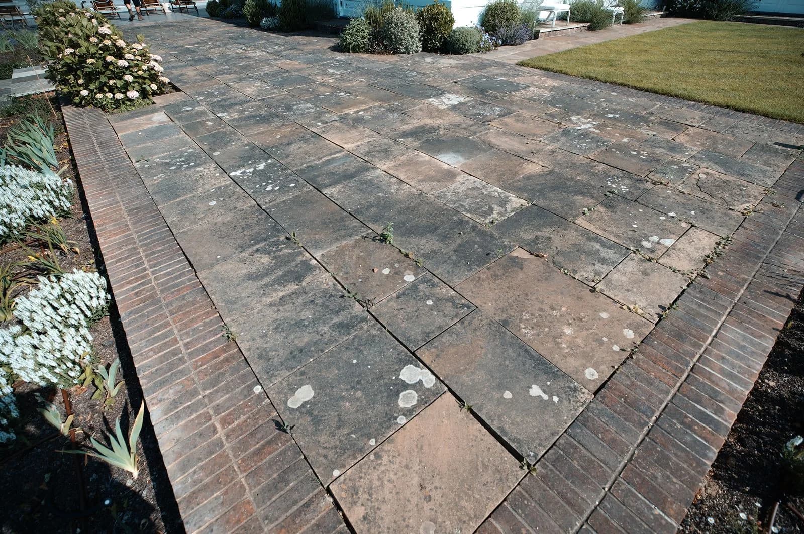 Dirty Indian sandstone paving and brick edging in Henley-on-Thames before cleaning