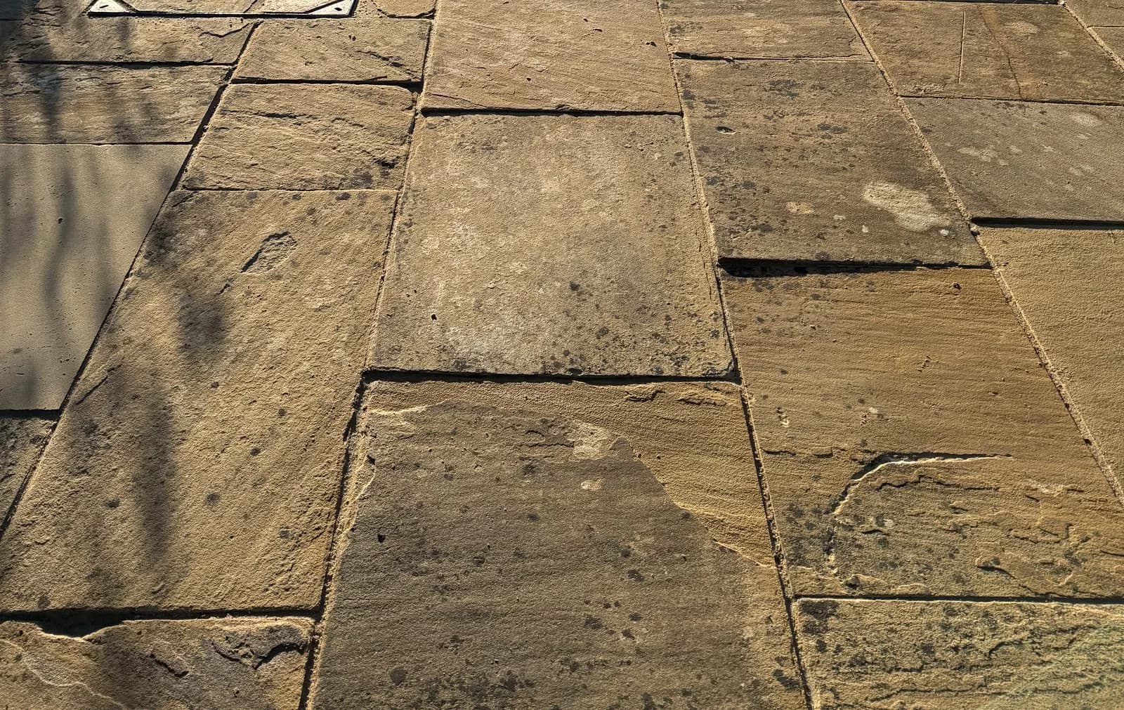 The even repointed joints running across the relaid Indian sandstone paving