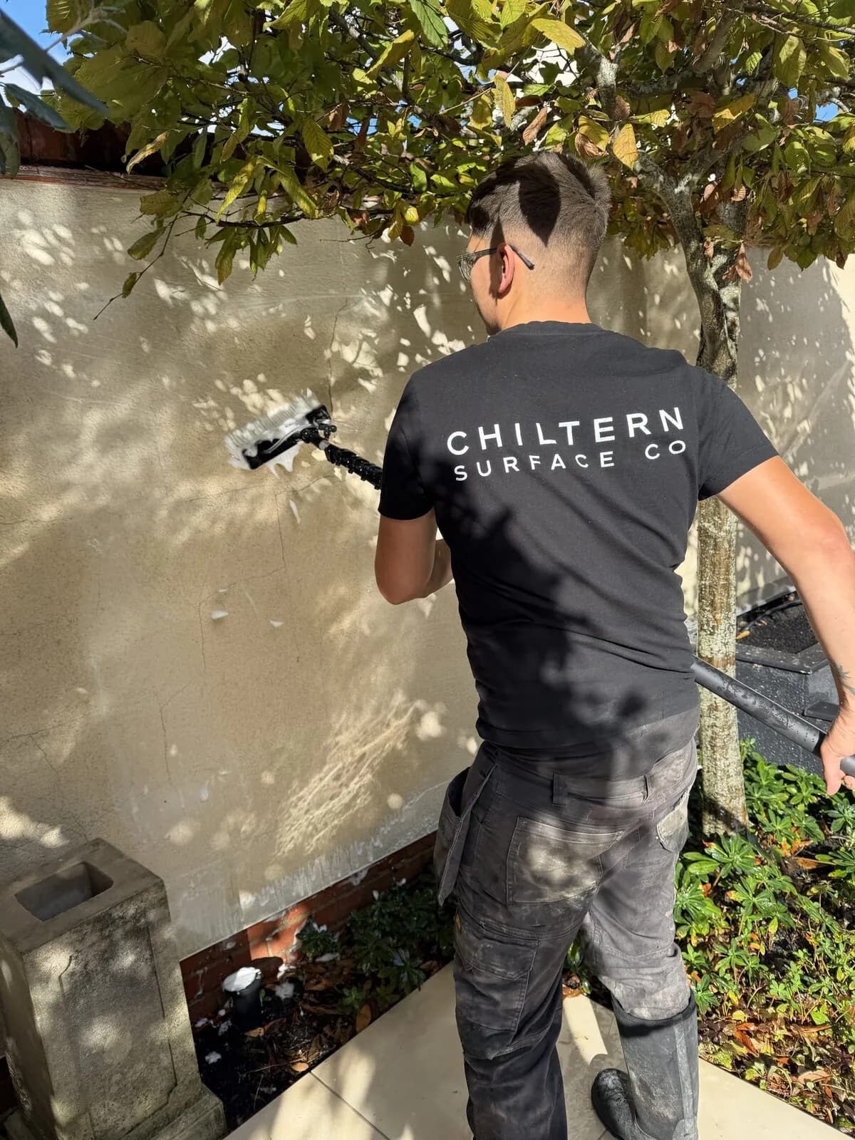 Chiltern Surface Co technician soft washing the rendered garden wall