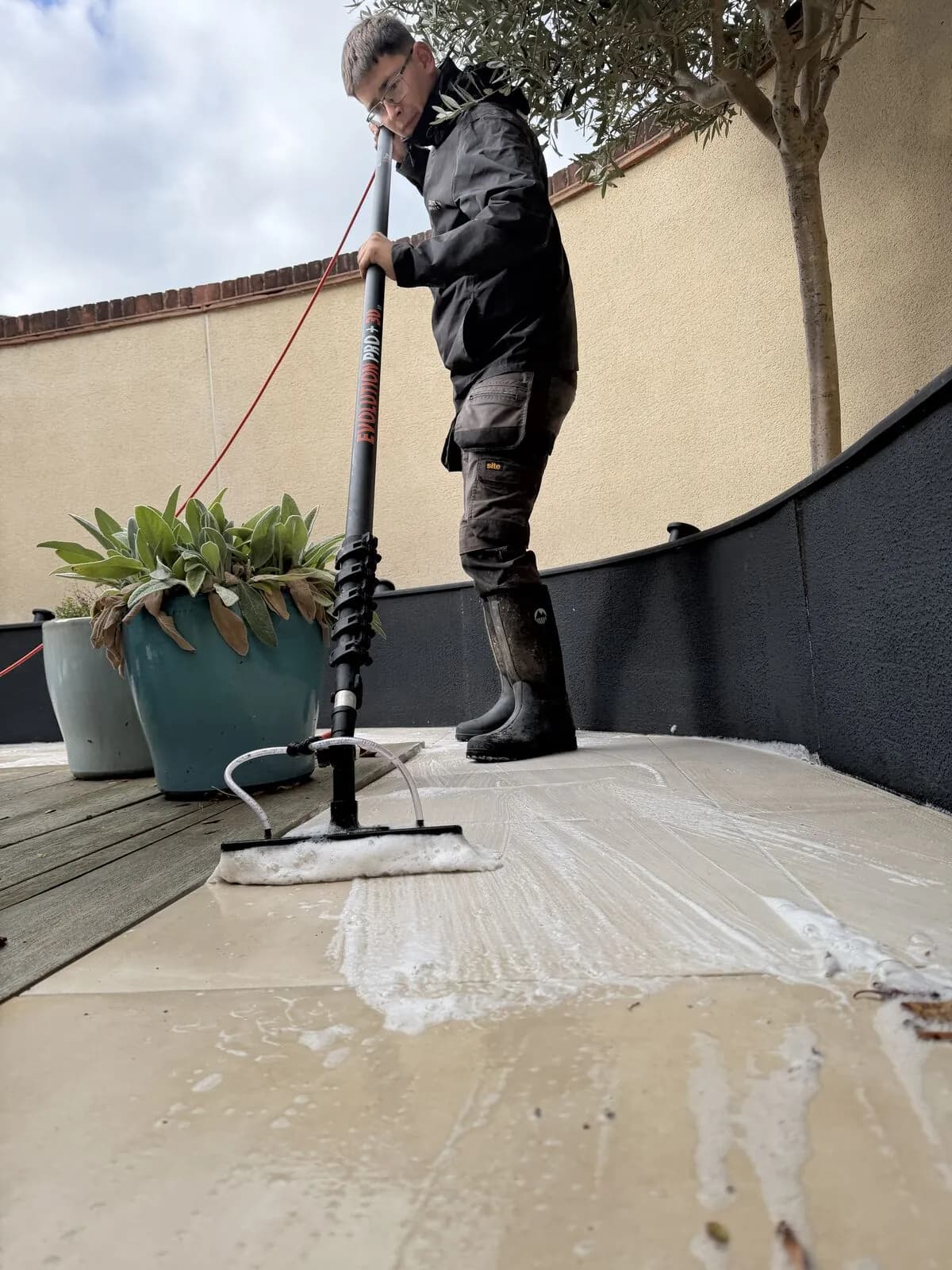 Soft washing the porcelain patio with a water-fed brush