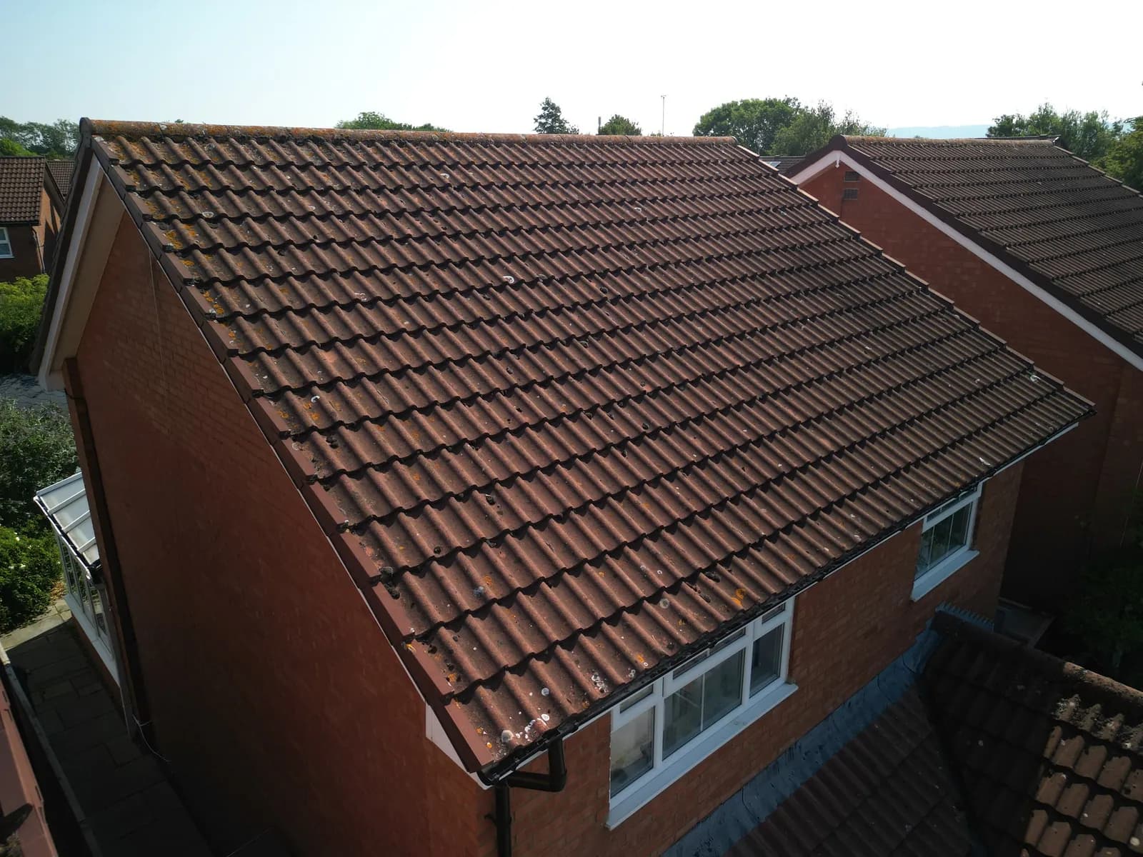 Detached house in Aylesbury with a moss-covered concrete tile roof before cleaning, seen from the drone