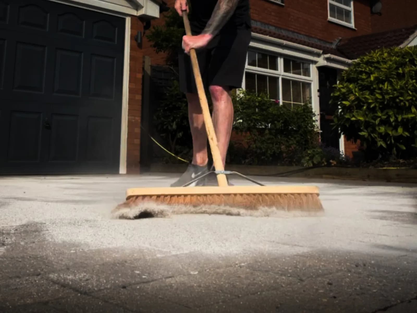 Polymeric jointing sand being brushed into the joints of a block paved driveway
