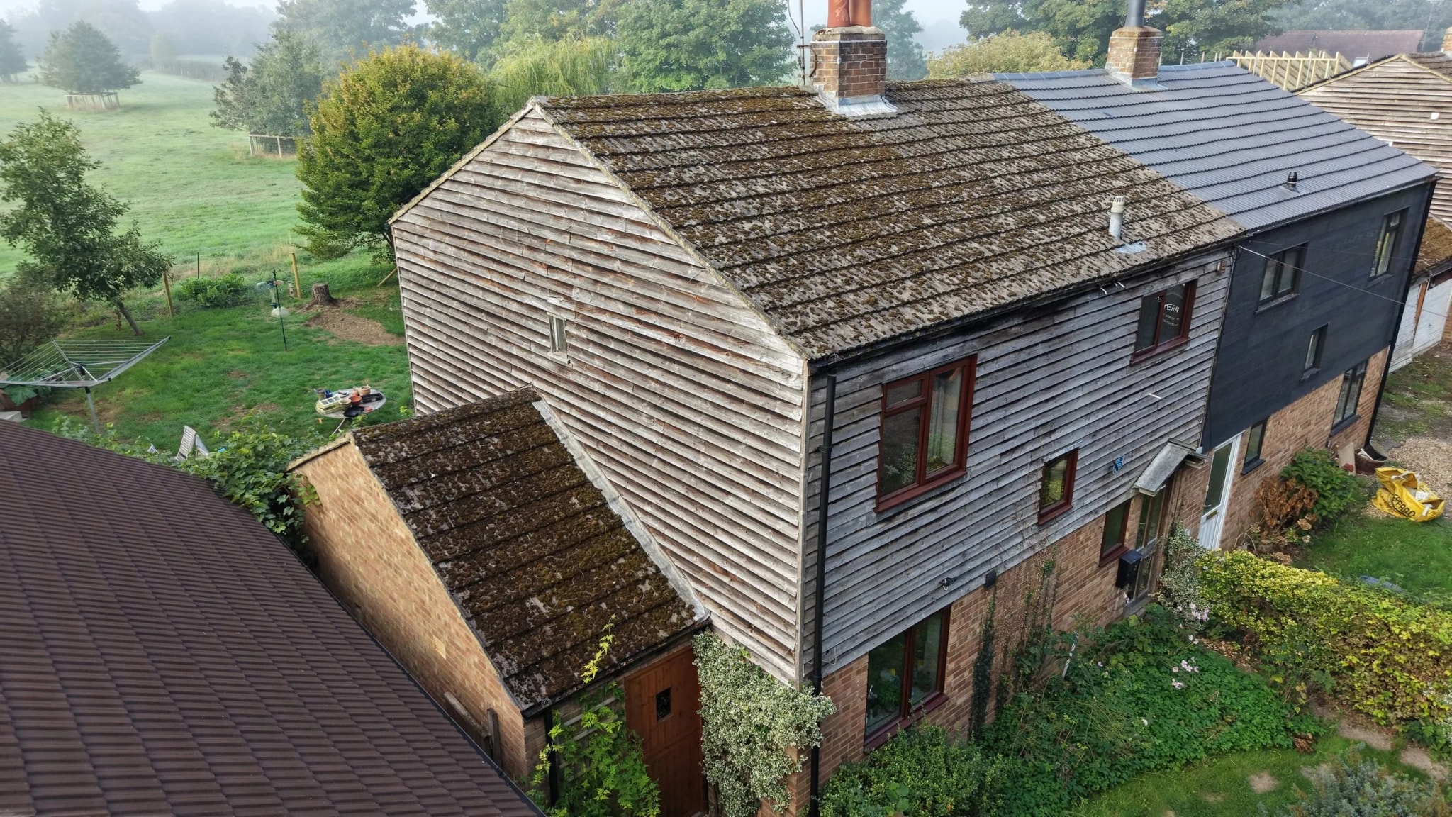Weatherboarded cottage in Henley-on-Thames with a concrete tile roof covered in moss before cleaning