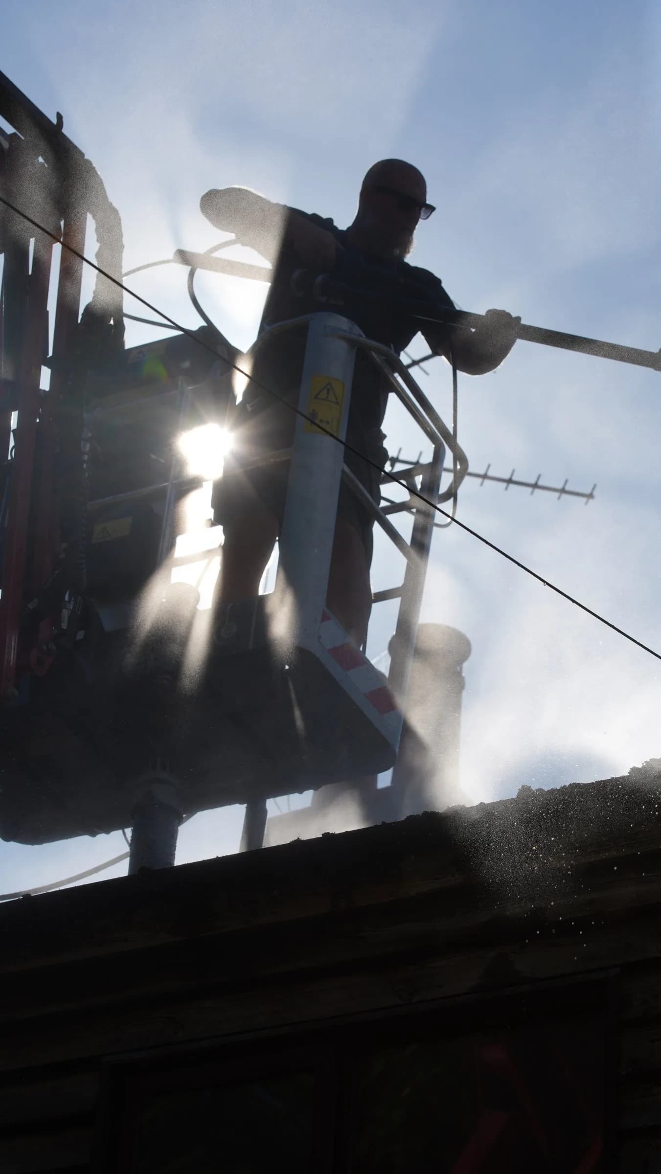 A Chiltern Surface Co technician applying Chiltern EverGuard™ to the roof from a spider lift basket
