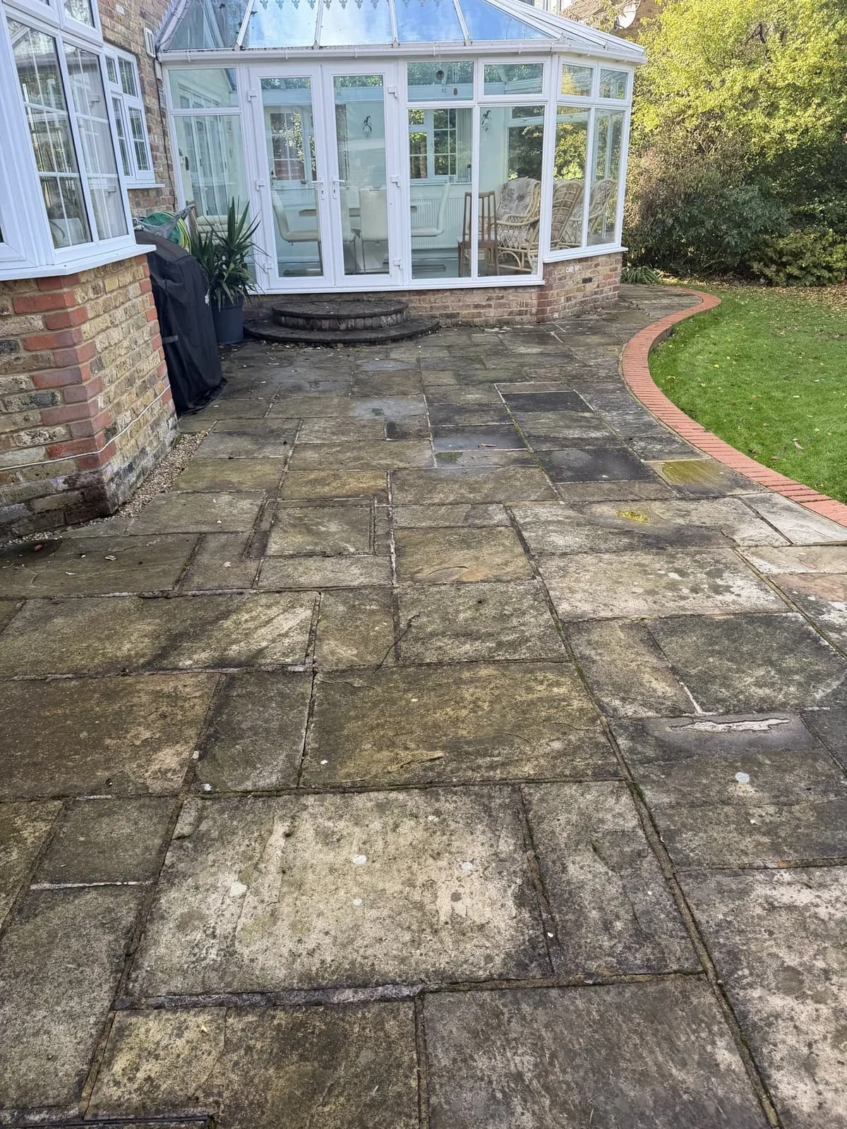 Indian sandstone patio in Princes Risborough before cleaning, the slabs dark with black spot lichen, algae and soiling