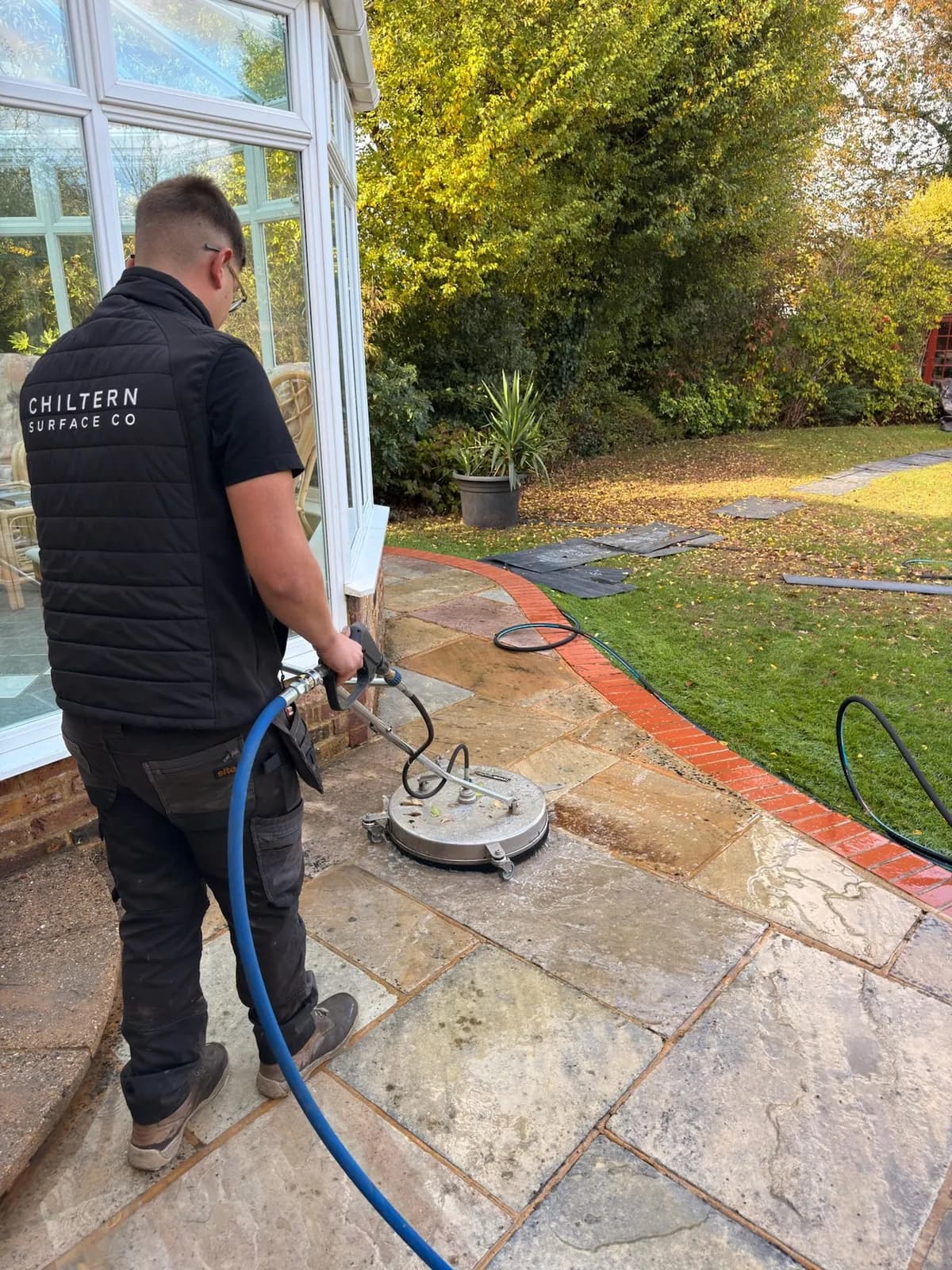 A Chiltern Surface Co technician restoration cleaning the sandstone patio with a commercial surface cleaner in Princes Risborough