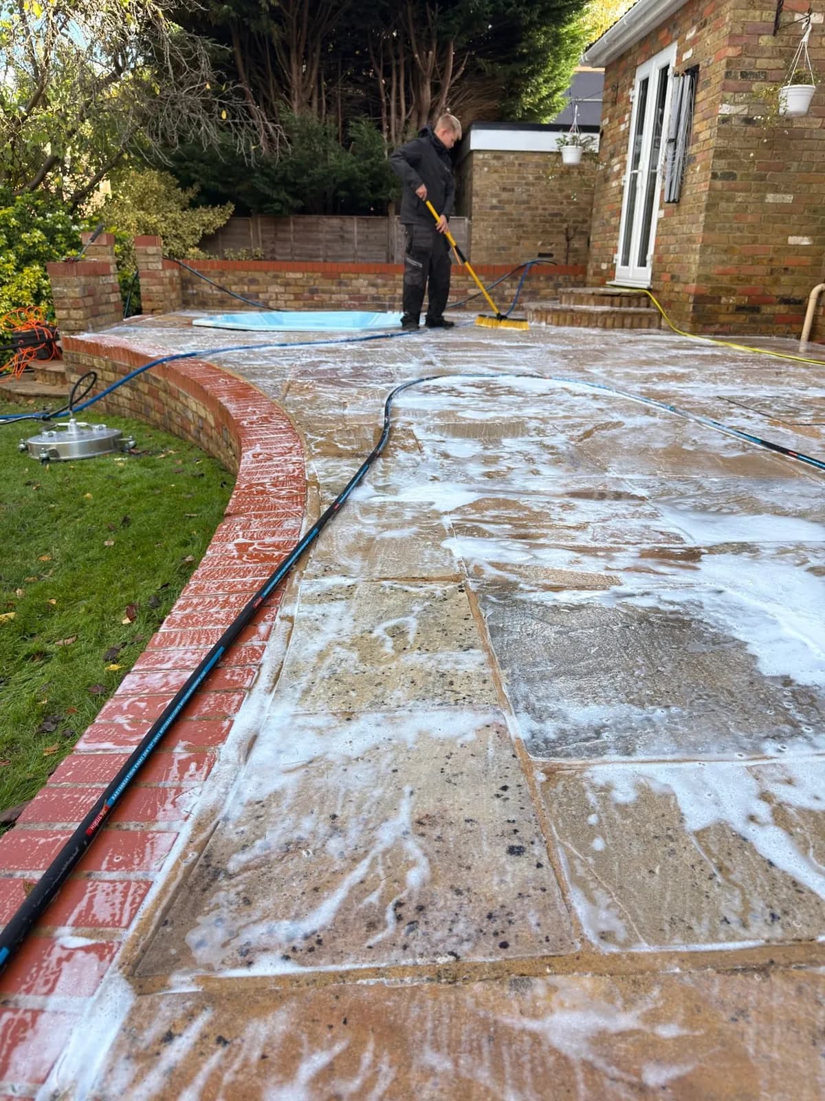 A Chiltern Surface Co technician applying black spot treatment across the cleaned sandstone patio in Princes Risborough