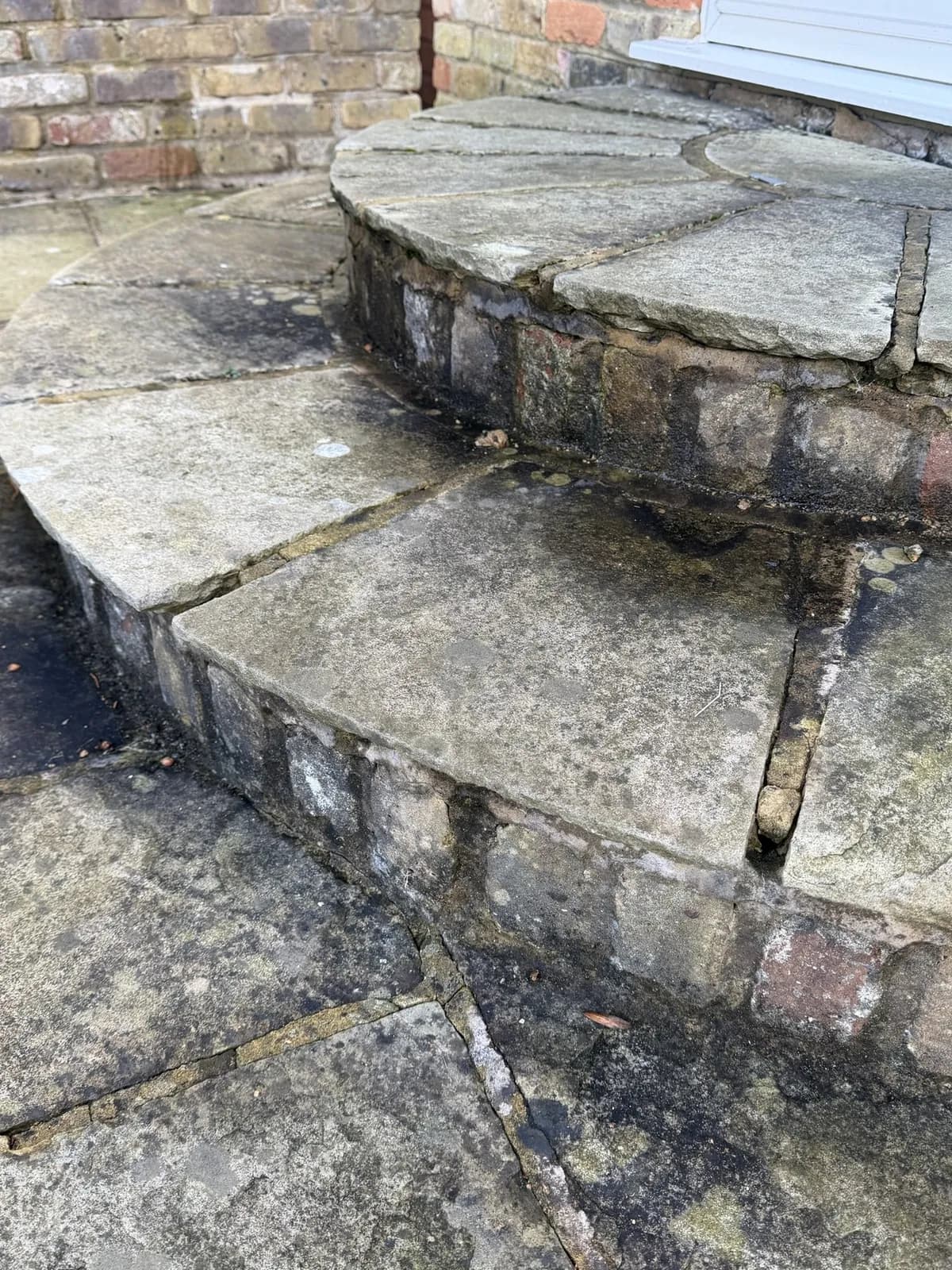 The semicircular sandstone back steps before the works, joints open and the risers black with growth