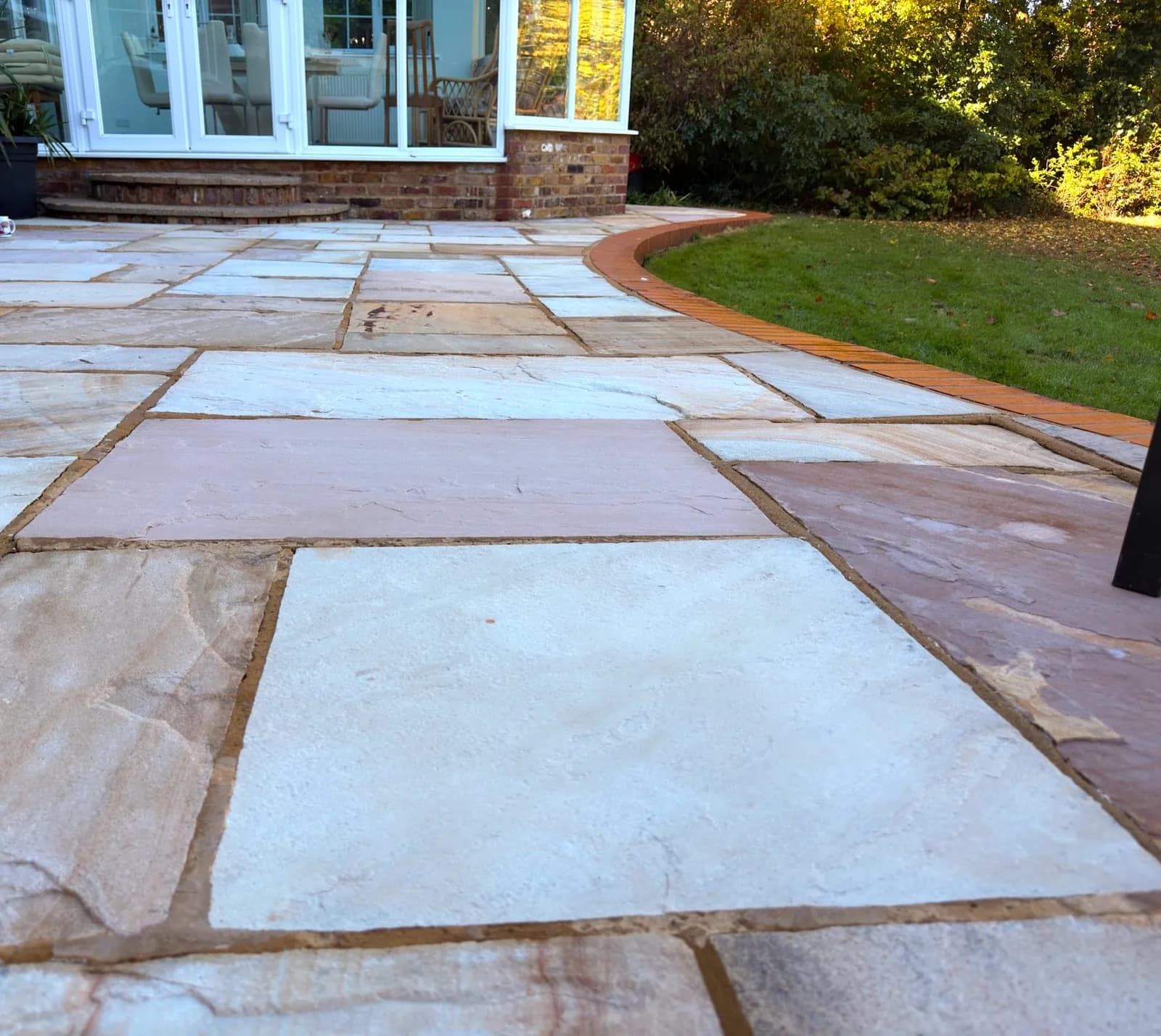 The finished sandstone patio in front of the conservatory in autumn sun, the colour back in every slab