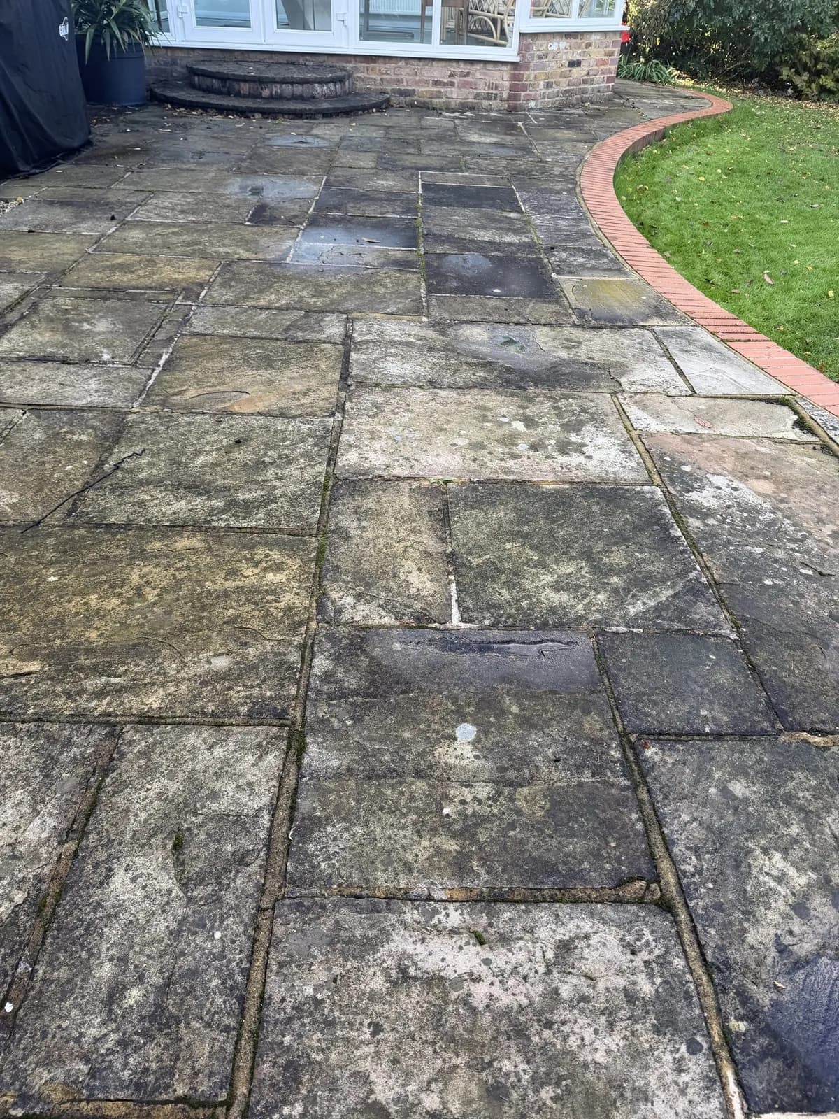 Sandstone slabs by the conservatory dark with growth and spotted with lichen, the day before the works