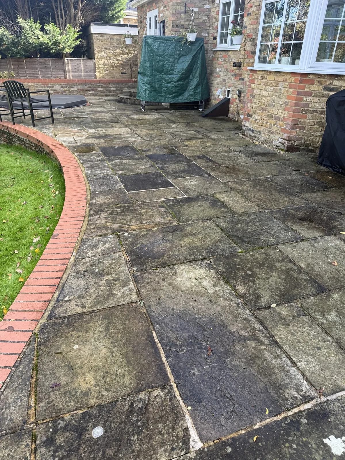 The sandstone patio along the curved brick edging in Princes Risborough the day before the works, dark with algae, lichen and soiling