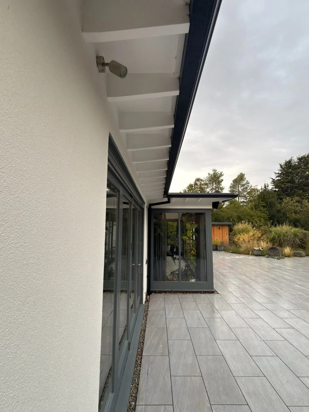 The soffit line and rear glazing after soft washing, running out to the restored porcelain patio and garden room