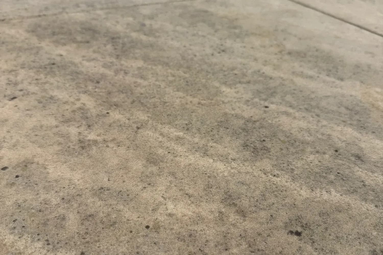 Close view of a concrete patio surface showing ingrained dirt and staining