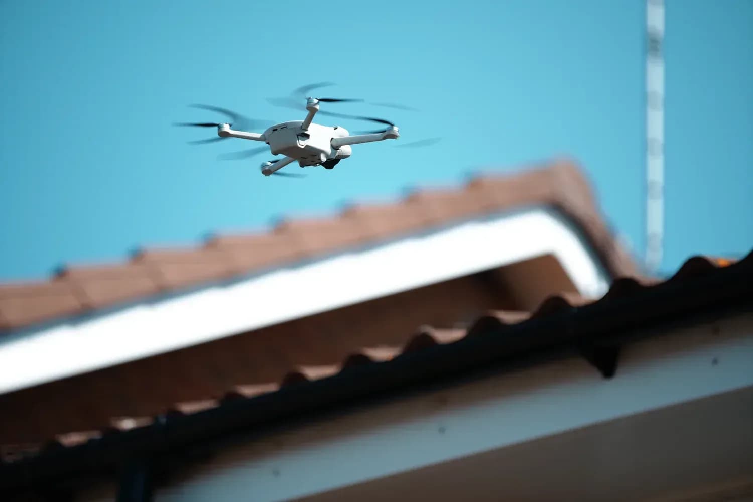 Drone hovering beside a roofline during a survey